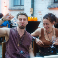 Two friends at an outdoor table making goofy faces, holding empty wine glasses at a street-side restaurant photo.